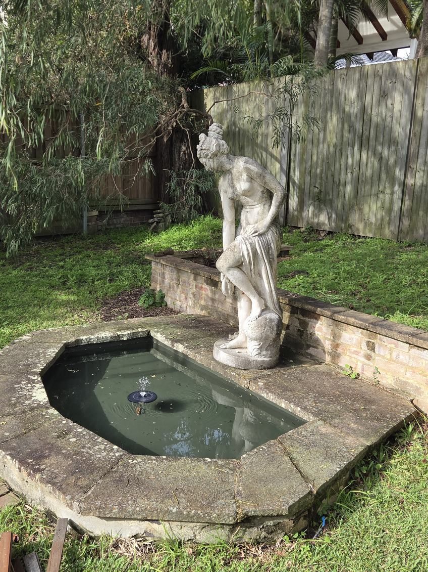 An ornamental garden pond and water feature with a statue